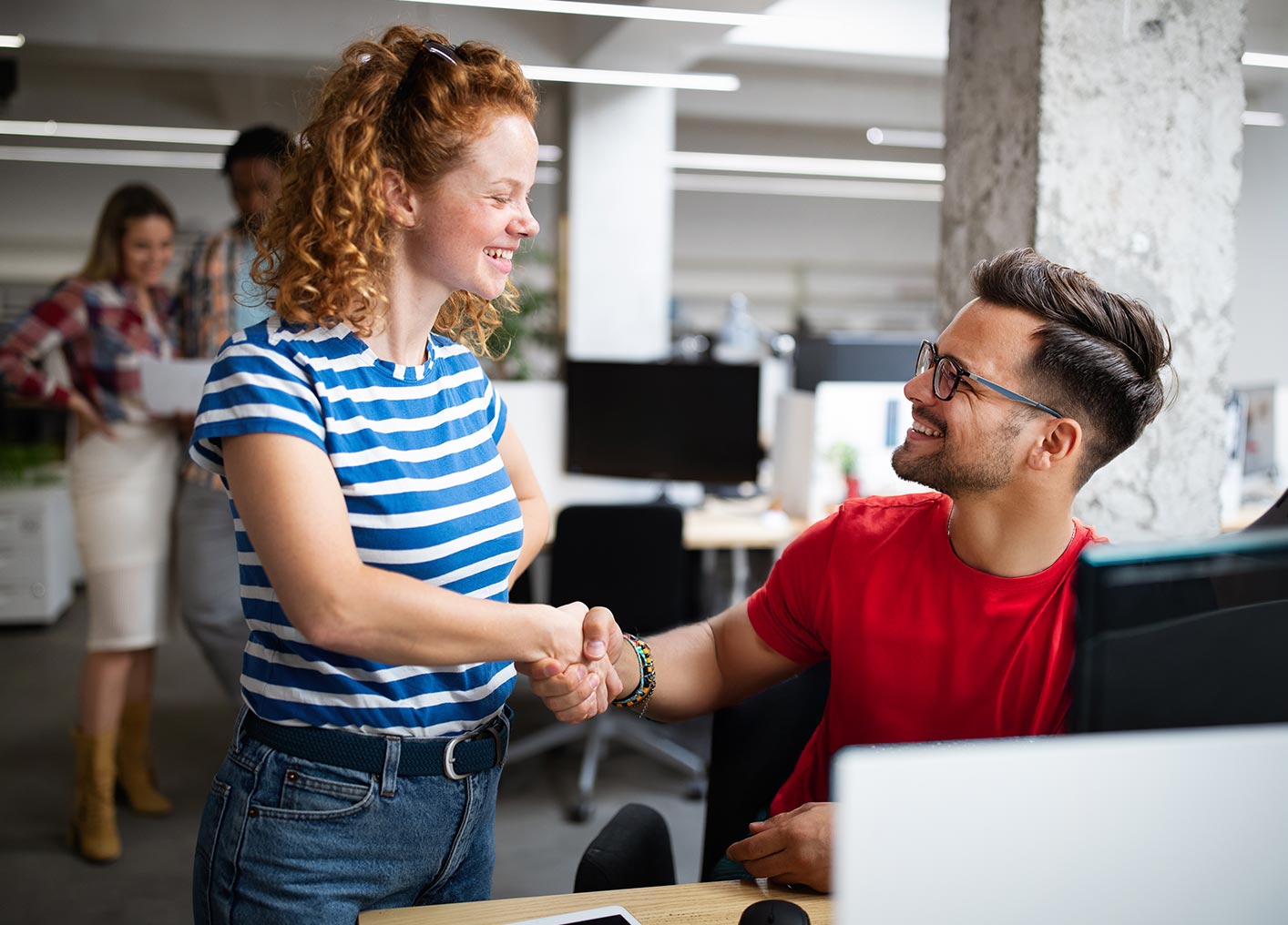 woman and man shaking hands in a business setting